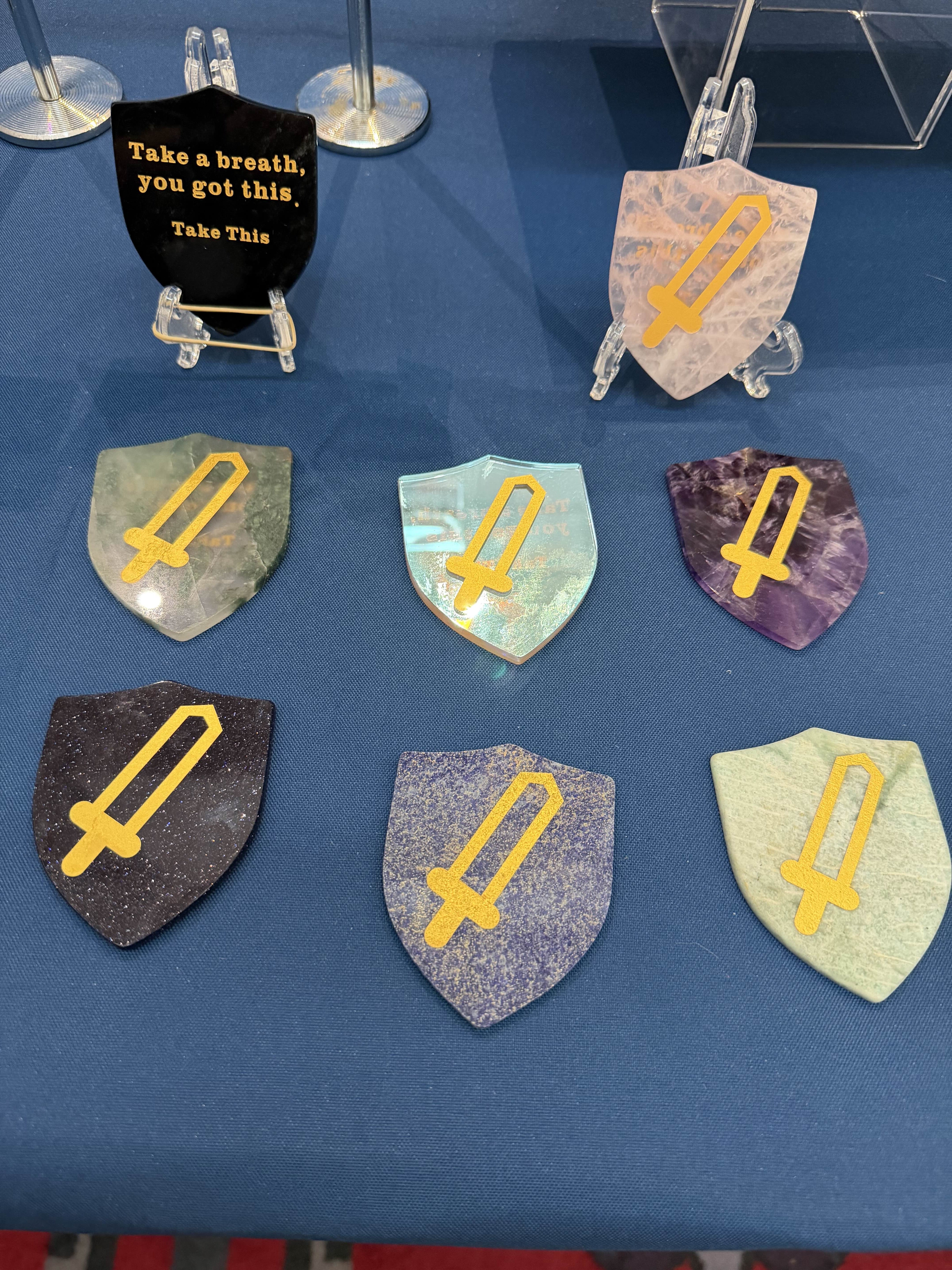 Decorative shields with yellow symbols on a blue surface, with a motivational sign in the background.